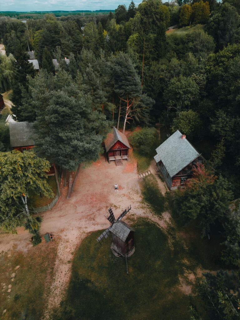 pexels photo 18261849 18261849 Aerial shot of traditional houses surrounded by lush green forest in Nowogród, Poland, during summer.