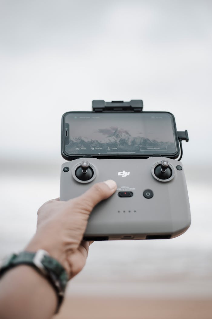 gallery-3 Close-up of a hand holding a drone controller with a smartphone displaying the camera view.